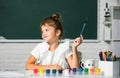 Child girl at school draws with paints. Kids artist creativity. Little funny artist painting, drawing art. Royalty Free Stock Photo