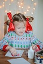 Child girl in seasonal sweater making christmas post cards