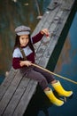 Child girl sits on wooden fishing bridge and catches fish. Royalty Free Stock Photo