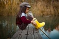 Child girl sits on wooden fishing bridge and catches fish with s Royalty Free Stock Photo