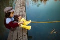 Child girl sits on wooden fishing bridge and catches fish with s Royalty Free Stock Photo