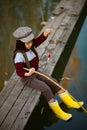 Child girl sits on wooden fishing bridge and catches fish. Royalty Free Stock Photo