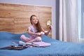 Child girl sitting on bed and playing with moms cosmetics, at home