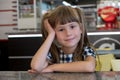 Child girl sitting in fast food restaurant behind empty table waiting for food Royalty Free Stock Photo