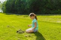 Child girl sitting and looking down on green grass field Royalty Free Stock Photo