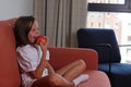 Child girl sitting on sofa with an apple, lifestyle stagging, healthy eating Royalty Free Stock Photo