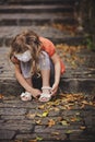 Child girl sitting on stone road with steps in warm autumn day Royalty Free Stock Photo