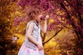 Child girl smells cherry flowers in spring garden