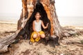 Child girl squatting in a large burnt hollow of a tree in which lightning hit