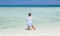 Child girl standing in tranquil, turquoise beautiful inviting ocean and feeding the fish