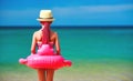 Child girl stands with her back with a Flamingo lifeline on beach