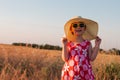 Child girl in straw hat dress in wheat field. Smiling kid in sunglasses sunset countryside. Cottagecore style aesthetic Royalty Free Stock Photo