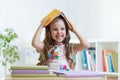 Child girl student in the school holds a book on her head