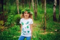 Child girl in summer forest. Idea for nature crafts with kids - leaf print shirt and natural wreath.