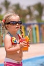 Child girl in sunglasses drink orange juice.