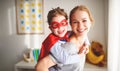 Child girl in a super hero costume with mask and red cloak