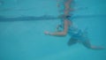 Child girl swimming in pool with toy skake in hand in tropical hotel, side view.