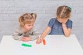 Child, a girl at the table writes, draws on a piece of paper, against a white brick wall Royalty Free Stock Photo