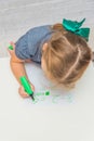 Child, a girl at the table writes, draws on a piece of paper, against a white brick wall Royalty Free Stock Photo