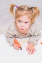 Child, a girl at the table writes, draws on a piece of paper, against a white brick wall Royalty Free Stock Photo