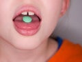 Child girl takes green pill. Teatment. Medicine eating.