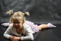 Child girl upset lying on the floor and crying on a black background