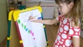 child girl using magnet board to learn letters and numbers at home