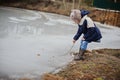 Child girl walking on frozen lake, started to melt in early spring day