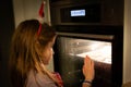 Child girl watching cookies baking in the oven at Christmas Royalty Free Stock Photo