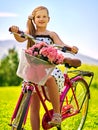 Child girl wearing white polka dots dress rides bicycle into park.