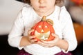 funny child girl in witch costume for Halloween holding a pumpkin lantrern