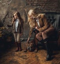 Child girl with woman in image of Sherlock Holmes read newspaper next to English bulldog on background of armchair and old interio Royalty Free Stock Photo