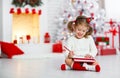 Child girl writing letter santa home near Christmas tree