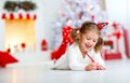 Child girl writing letter santa home near Christmas tree