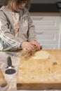 Child flattening some pizza dough with a rolling pin