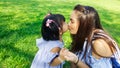 Child give flower to mom and kiss with love on green grass in park Royalty Free Stock Photo