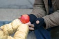Child gives apple to the beggar