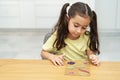 Child with glass picture frame, leaves, and flowers making herbarium on dining wood table in home. Royalty Free Stock Photo