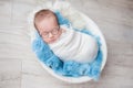 Child with glasses, newborn baby boy in a cocoon in a white bowl on a blue rug Royalty Free Stock Photo