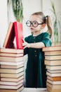 Child in glasses with pile of books, vertical