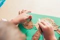 Child glues an applique made of autumn leaves