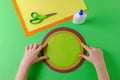 Child glues two circles with color paper, glue and scissors