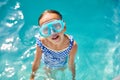 A child in goggles on the steps climbing out of the pool