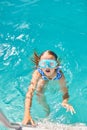 A child in goggles on the steps climbing out of the pool