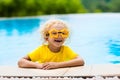 Child with goggles in swimming pool. Kids swim.