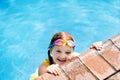 Child with goggles in swimming pool. Kids swim.