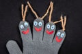 Child gray glove made of fabric with funny googly eyes and antennae smiling, handmade concept of art and creativity on black paper