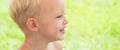 Child on the green grass in summer park. Baby face closeup. Funny little kid boy close up portrait. Blonde kid, smiling Royalty Free Stock Photo