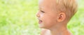 Child on the green grass in summer park. Baby face closeup. Funny little kid boy close up portrait. Blonde kid, smiling Royalty Free Stock Photo