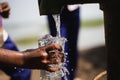 Child hand collecting fresh drinking water from local tube-well. A hand of a kid collecting drinking water with a glass. Royalty Free Stock Photo